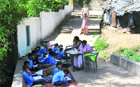 Slum-children study under the shade of a tree on a pathway in the Panjthirthi area of Jammu. A shanty in the background is used by the teachers to cook midday meal for schoolchildren. 