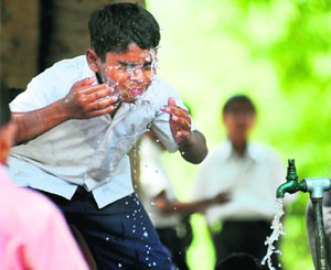 A schoolkid sprinkling water on his face to beat the heat outside Government Model Senior Secondary School, PAU, Ludhiana.