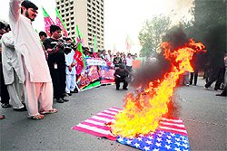 Protesters burn a US flag during a demonstration against the government's plan to reopen NATO supplies route in Islamabad on Tuesday