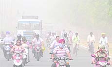 Commuters endure hazy and dusty conditions on a road in Chandigarh on Thursday.