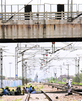 Unaware of the risk involved, people rest under a flyover on a railway track in Karnal.