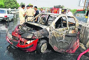 The mangled remains of the Indica car that caught fire on the flyover in Kurukshetra on Saturday. The driver and two other occupants, residents of Yamunanagar, escaped unhurt