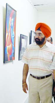 A man takes keen interest in the paintings exhibited at an art gallery in Amritsar on Monday.