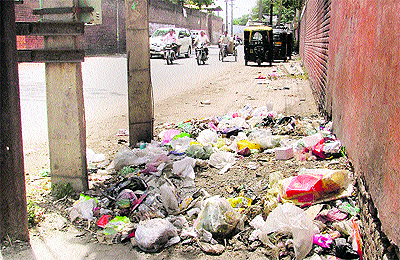 Garbage being dumped on a roadside at New Deep Nagar, high-tension wires cross through roofs of the houses and a view of the poor condition of a road in ward number 30