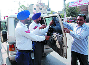 Traffic police personnel remove the black film from the glasses of a vehicle at Hanuman Chowk in Bathinda on Wednesday. As per an order passed by the Supreme Court, black films with any percentage of tint are not allowed anymore. Earlier this month, Bathinda SSP, Sukhchain Singh Gill had instructed the traffic cops to give warning to the owners of vehicles with tinted glasses to remove the films by May 11. 