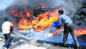 Shopkeepers throw water to douse the fire behind the showrooms in Sector 7, Chandigarh, on Thursday.