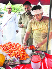 A vendor sells cut fruits near the vegetable market in Karnal.