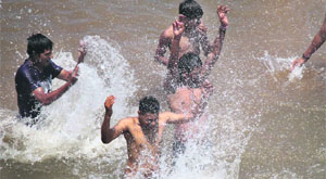 Youths take a splash in the Tawi to beat the heat in Jammu on Thursday. 