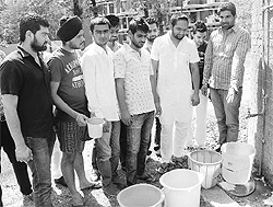 Students show empty buckets at Panjab University in Chandigarh on Friday