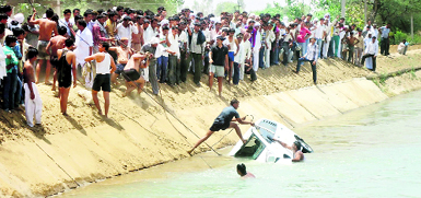 People try to bring out a car which fell into the Sirsa branch canal on NH-71A near Narwana while crossing over a bridge on Friday.