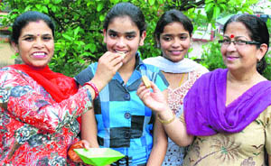 Commerce topper Tanuja Kumari is offered sweets by her mother in Dharamsala on Friday.
