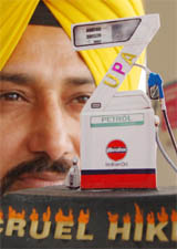 Artist Dr Harwinder Singh Gill shows his miniature model of a petrol pump to lodge protest against the petrol price hike in Amritsar on Saturday. 