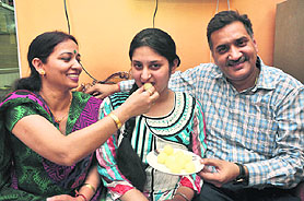 Principal of JK Montessori School offers sweets to Palvi Verma who has stood third in the class X results in Jammu on Saturday. Palvis father is also seen in the picture.