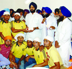 Bikram Singh Majithia presents a cheque to a youth club in Kaler Bala village.