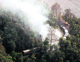 A toy train passes near a forest fire on the Kalka-Shimla railway track in Shimla on Sunday.