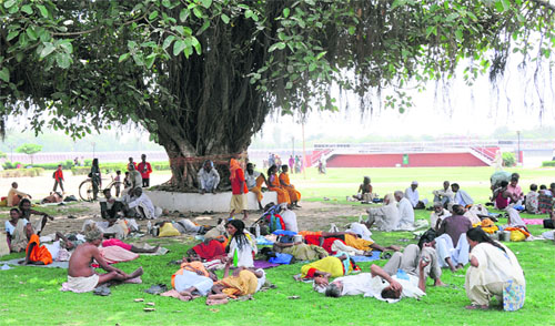 Sadhus and visitors take refuge under a tree during a hot afternoon on the banks of Brahmasarovar in Kurukshetra