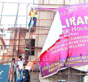 MC workers remove illegal hoardings from the area around the Golden Temple in Amritsar on Wednesday