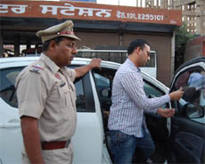 A police personnel makes an owner remove the black film from the windowpane of his vehicle in Bathinda on Wednesday.