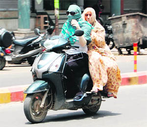 Scooter riders cover themselvesto save their skin from the sizzling heat in Amritsar on Thursday.