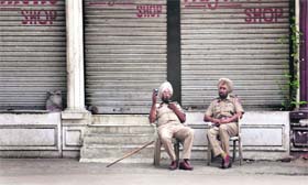 Policemen sit outside some shops that were closed following the bandh call in Ludhiana on Thursday