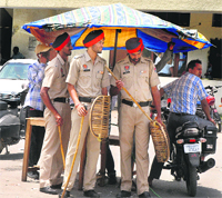 Policemen take shelter under an umbrella. Tribune photo: Malkiat Singh
