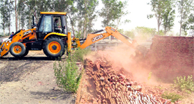 A ditch machine uprooting a road of an illegal colony during a demolition drive by GLADA in Ludhiana on Saturday.