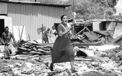 A woman runs to collect her belongings during a demolition drive by MC officials in a slum in Thane in Mumbai 