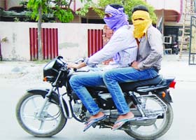 Two youths cover their faces while riding a bike on a hot summer afternoon in Amritsar on Monday