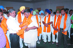 Chief Parliamentary Secretary Sarup Chand Singla presents a siropa (robe of honour) to one of the seven Congressmen who joined the SAD in Bathinda on Monday.