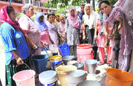 Women line up to fetch water at Milk Colony in Dhanas on Monday. 