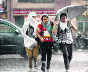 Girls enjoy a sudden downpour that brought relief from the sweltering heat in Dehradun on Monday. 