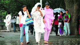 Girls walk during a mild thundershower in Shimla on Monday.