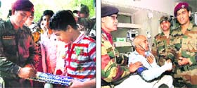 Indian cricket team captain MS Dhoni gives an autograph to a schoolstudent in Srinagar on Monday; and (right) Dhoni shakes hands with a patient at an Army hospital