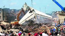 People watch a crane lift the tail of the ill-fated plane that crashed in Lagos on Sunday.