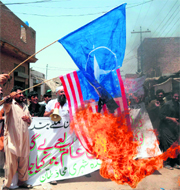 Protesters burn US and NATO flags during a demonstration against drone attacks in Multan on Monday.