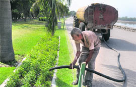A gardener uses a water tanker of the horticulture department to water plants at Sukhna Lake, Chandigarh, on Tuesday.