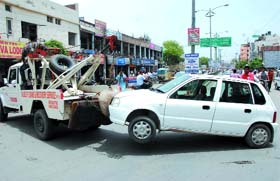 A wrongly parked car being towed away by traffic police personnel near the railway station in Bathinda on Wednesday