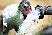 A man quenches his thirst from a tube well in the hot weather