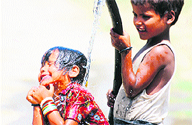 A girl enjoys a bath from a water pipe to get relief from the scorching heat in Karnal. 