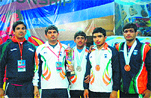 Players of the Indian Wrestling Team, along with their coach, hold the trophy during the Asian Junior Wrestling Championship in Kazakhstan. 