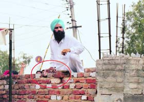 A party worker with a brick in his hand tries to scale the wall of a polling station in Muktsar