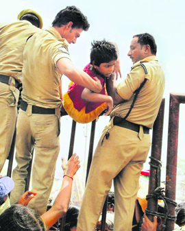 Policemen help a child following a stampede after asthma patients jostled to receive traditional fish medicine from the Bathini Goud family at Kattedan village in Ranga Reddy district, Andhra Pradesh, on Friday. One person died and over 20 were injured.