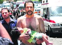 A Syrian man carries a wounded girl following an explosion that targeted a military bus near Qudssaya on Friday.