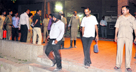 Officials of Jammu University and the Fire Department come out from the examination branch soon after fire was doused on Friday night.