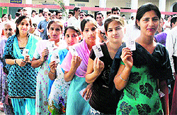Residents stand in a queue to cast their vote at a polling station in Patiala on Sunday