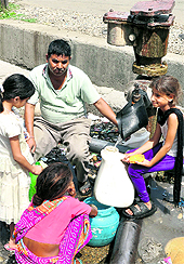 ocal residents fetch water for daily use from a water supply pipe on the roadside at Narwal in Jammu on Sunday