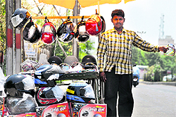 A vendor sells helmets at a roadside stall in Jammu