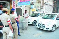 Traffic police personnel issue a challan to a car parked outside the yellow line, the designated area for parking, on a road in Bathinda