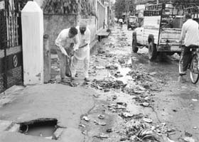 Residents try to open a blocked drain on the Gulabgarh road in Dera Bassi