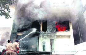Firemen douse the fire that engulfed an apparel showroom on Rajpur Road in Dehradun on Monday